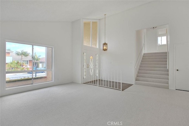 unfurnished living room featuring carpet floors and stairs