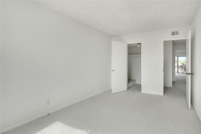 unfurnished bedroom with visible vents, carpet floors, and a textured ceiling