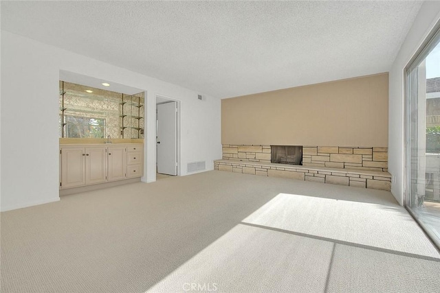 carpeted living area featuring visible vents and a textured ceiling