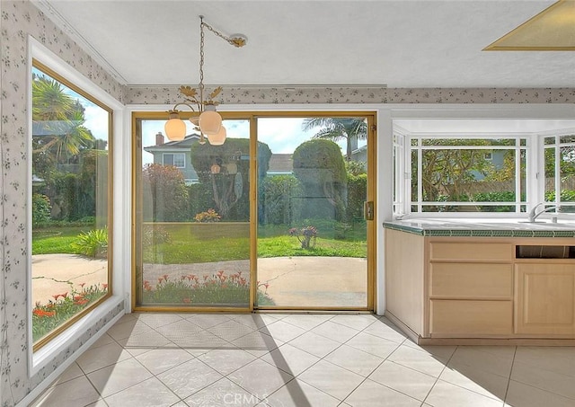 interior space featuring an inviting chandelier, light tile patterned floors, a sunroom, and a sink