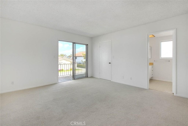 empty room featuring light colored carpet, baseboards, and a textured ceiling