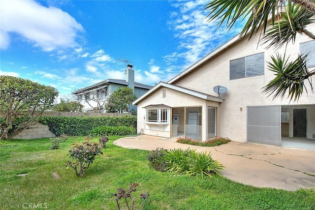 rear view of property with stucco siding, a patio, a lawn, and fence