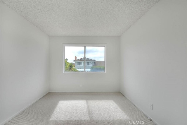 unfurnished room featuring light carpet, baseboards, and a textured ceiling