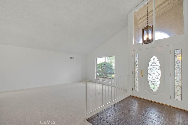 foyer featuring a chandelier, visible vents, a textured ceiling, and high vaulted ceiling