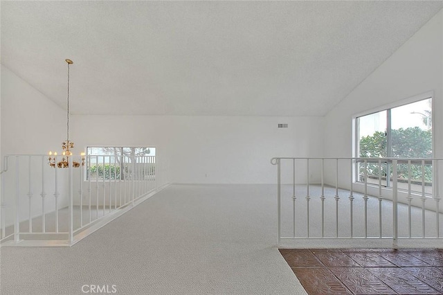 hall featuring lofted ceiling, carpet, visible vents, and a chandelier