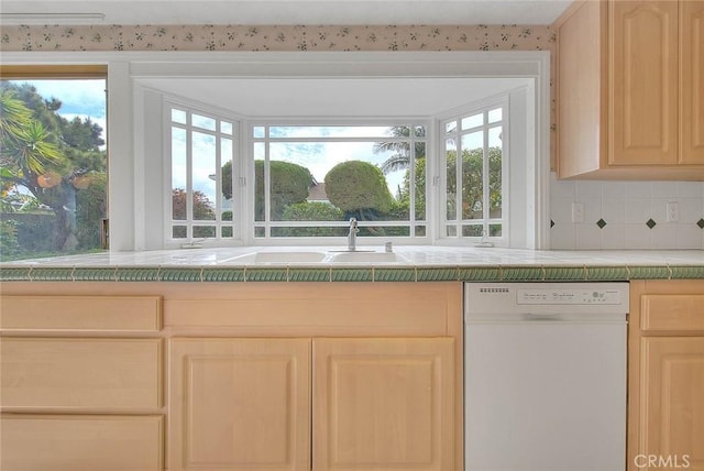 kitchen featuring light brown cabinets, plenty of natural light, white dishwasher, a sink, and tile counters