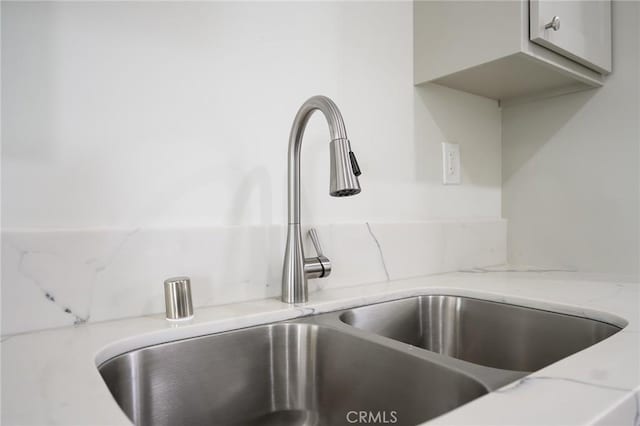 details featuring a sink and light stone countertops