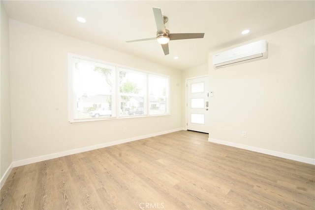 empty room with baseboards, recessed lighting, light wood finished floors, and a wall mounted AC