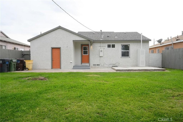 rear view of house with stucco siding, a patio area, a fenced backyard, and a yard