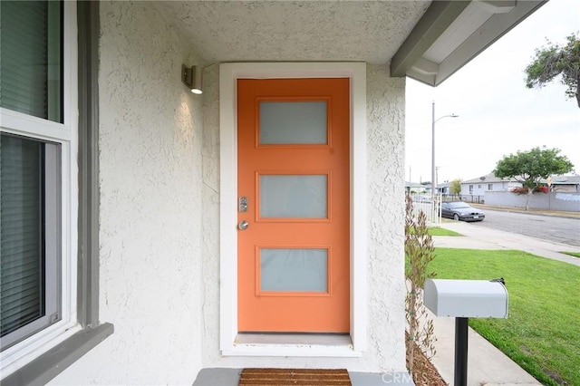 doorway to property with stucco siding and a yard