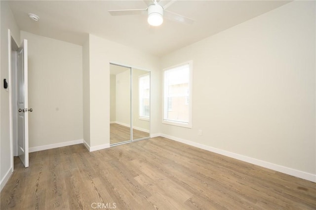 unfurnished bedroom with a ceiling fan, baseboards, light wood-style floors, and a closet