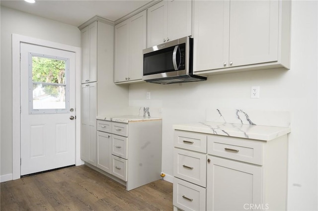 kitchen featuring dark wood finished floors, light stone countertops, and stainless steel microwave