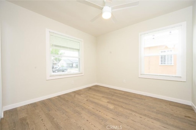 spare room with baseboards, ceiling fan, and light wood-style flooring