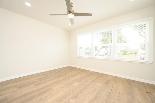 spare room with a wealth of natural light, baseboards, and light wood-style floors