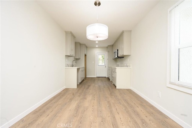 kitchen featuring baseboards, decorative light fixtures, and light countertops