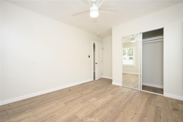 unfurnished bedroom featuring baseboards, a ceiling fan, light wood finished floors, and a closet