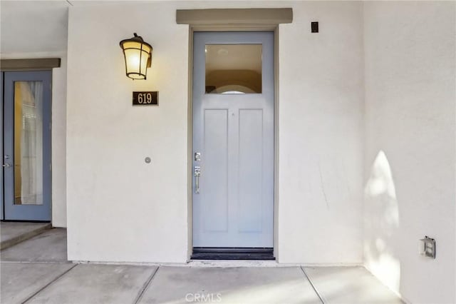 doorway to property featuring stucco siding