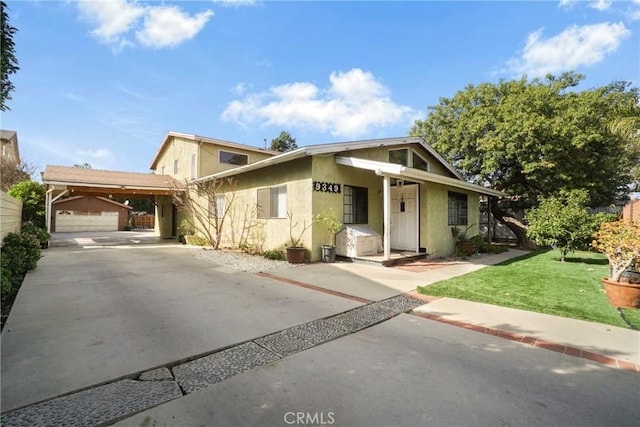 view of front of property featuring a garage, an outdoor structure, a carport, and a front yard