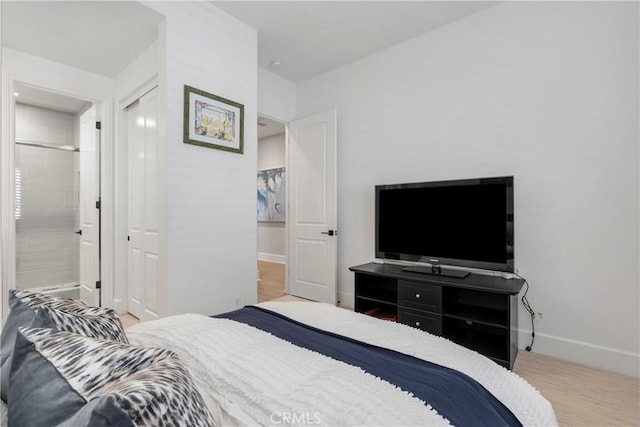 bedroom featuring ensuite bath, a closet, and hardwood / wood-style floors