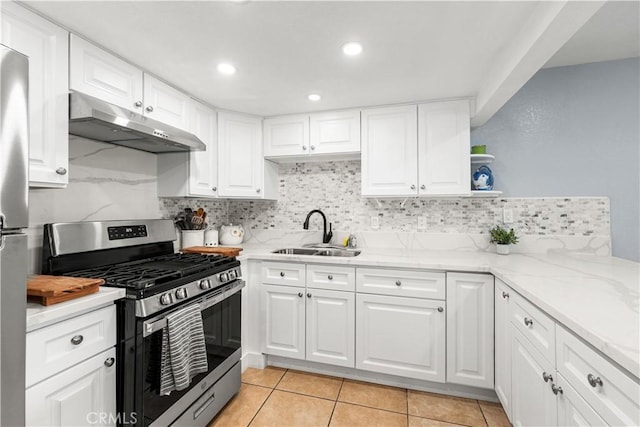 kitchen with appliances with stainless steel finishes, tasteful backsplash, light stone countertops, white cabinets, and sink