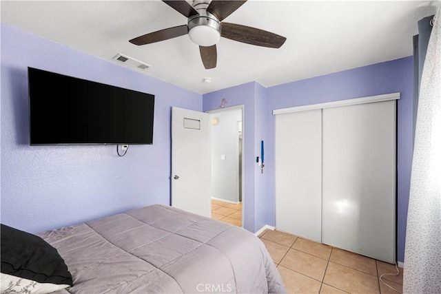 tiled bedroom featuring ceiling fan and a closet