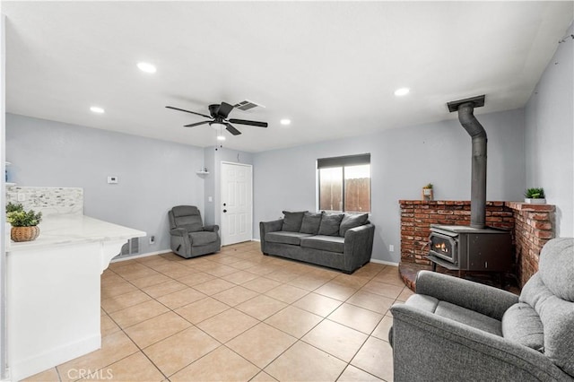 tiled living room with a wood stove and ceiling fan