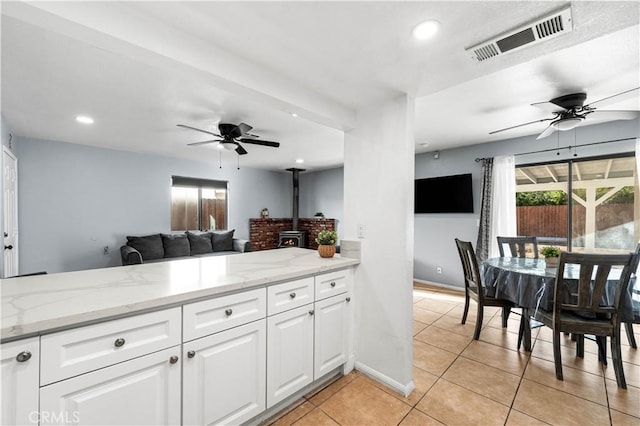 kitchen featuring light stone counters, white cabinets, and a healthy amount of sunlight