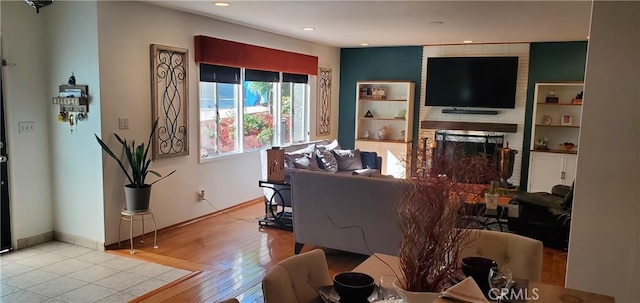 living area featuring light wood-style flooring, a fireplace, baseboards, and recessed lighting