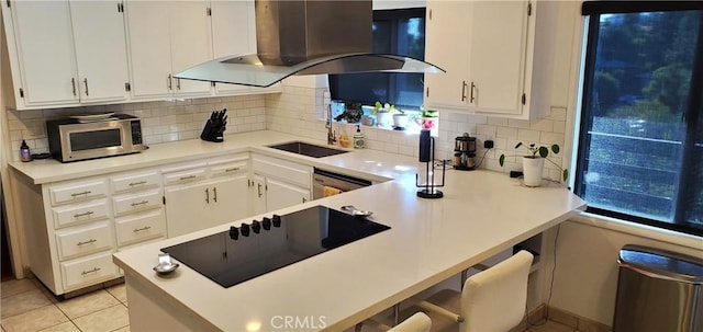 kitchen featuring white cabinetry, light countertops, appliances with stainless steel finishes, backsplash, and island exhaust hood