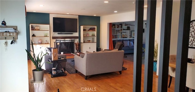 living area with a large fireplace, wood finished floors, and recessed lighting