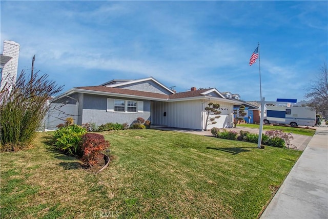 single story home with a garage, driveway, a front yard, and stucco siding