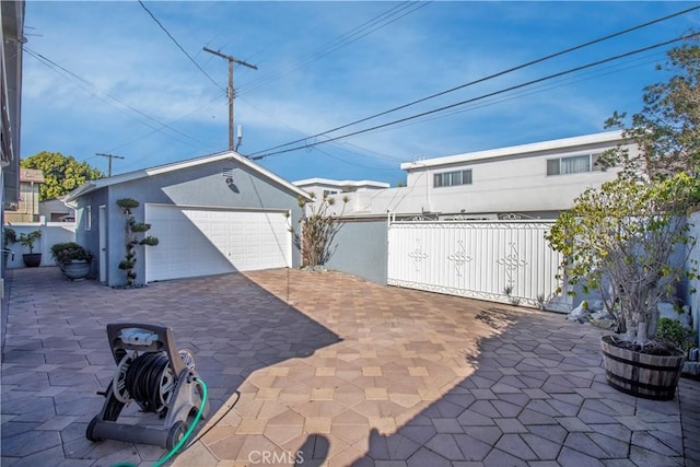 view of patio / terrace featuring a garage, an outbuilding, and fence