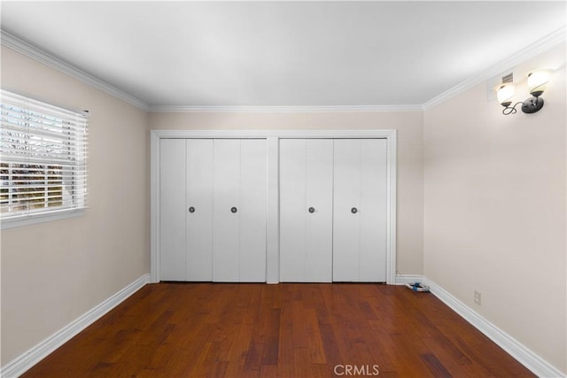 unfurnished bedroom featuring crown molding, wood finished floors, and baseboards