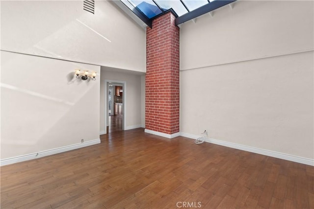 interior space with wood finished floors, a towering ceiling, and baseboards