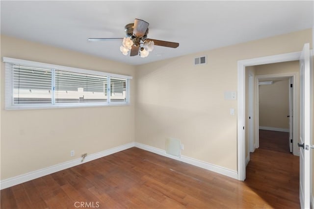 empty room with baseboards, visible vents, ceiling fan, and wood finished floors