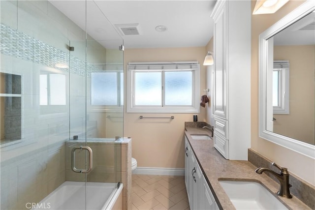 bathroom with double vanity, baseboards, toilet, and a sink