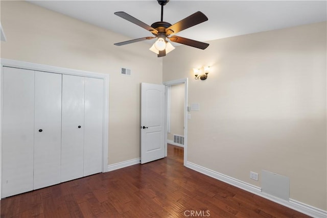 unfurnished bedroom with a closet, visible vents, baseboards, and wood finished floors