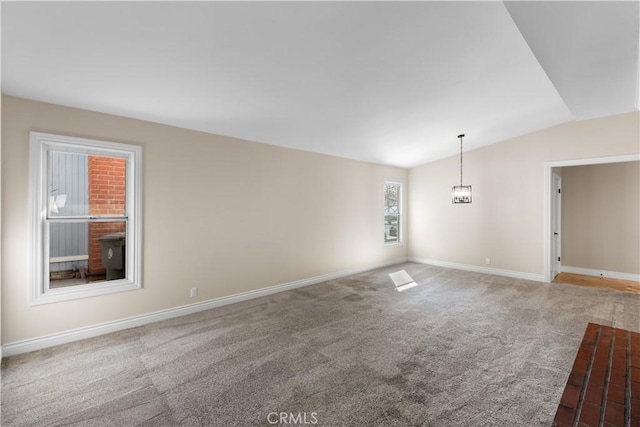 carpeted empty room with vaulted ceiling and baseboards