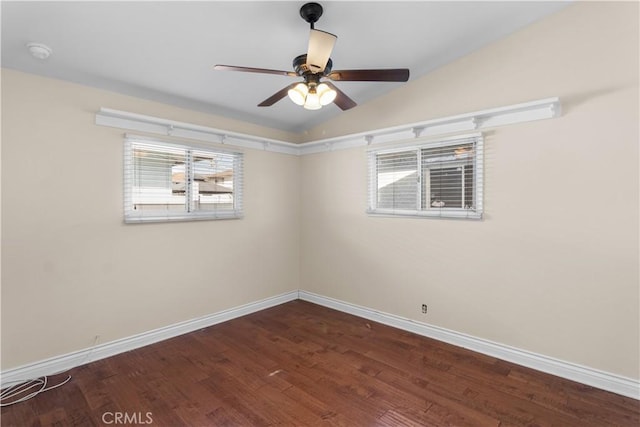 empty room featuring a ceiling fan, lofted ceiling, dark wood finished floors, and baseboards