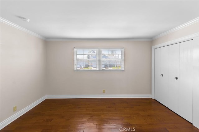 unfurnished bedroom with baseboards, a closet, ornamental molding, and wood finished floors