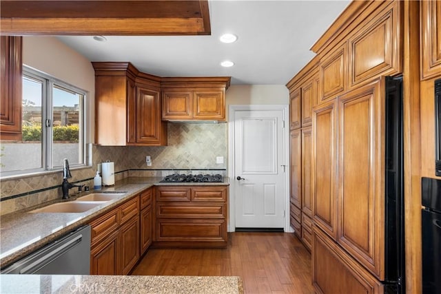 kitchen featuring stainless steel dishwasher, a sink, and brown cabinets