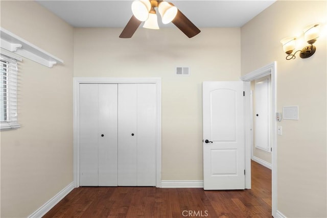 unfurnished bedroom featuring baseboards, a closet, visible vents, and wood finished floors