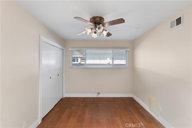 empty room featuring visible vents, ceiling fan, baseboards, and wood finished floors