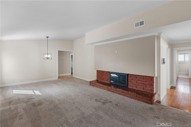 unfurnished living room with a brick fireplace, visible vents, baseboards, and carpet flooring