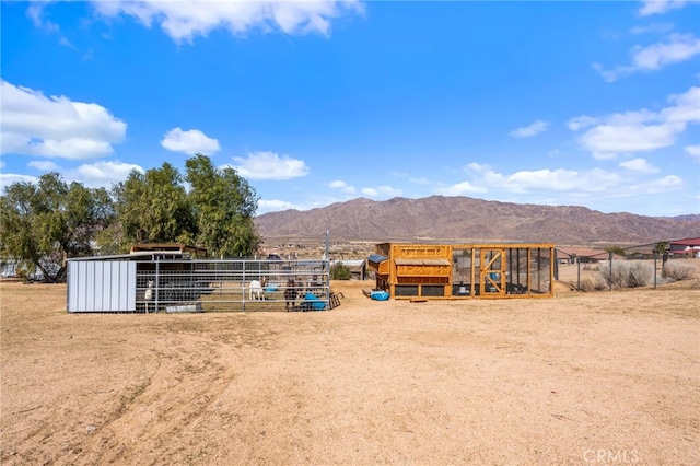 view of yard featuring a rural view, an outbuilding, and a mountain view