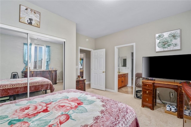 bedroom with a closet, light carpet, and ensuite bath