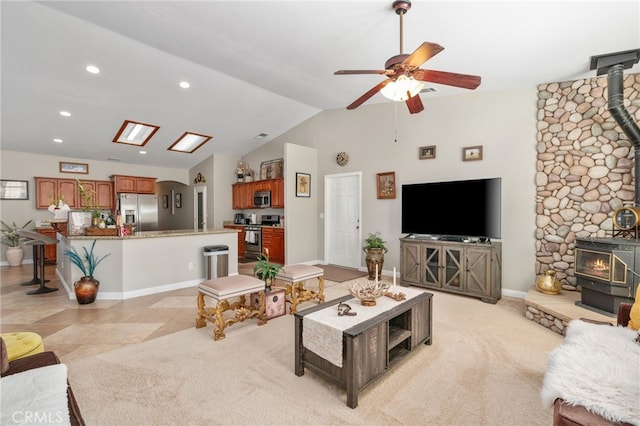 carpeted living room featuring ceiling fan, vaulted ceiling, and a wood stove