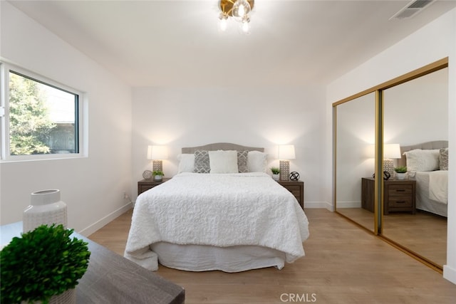 bedroom featuring light wood finished floors, a closet, visible vents, and baseboards