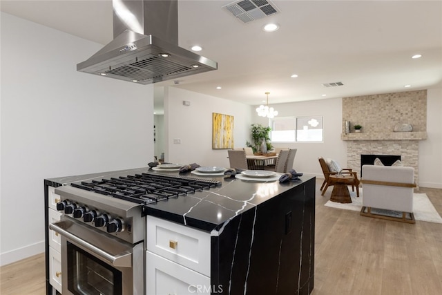 kitchen featuring visible vents, island range hood, a center island, high end stainless steel range oven, and white cabinetry