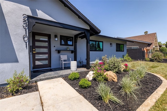 doorway to property with fence and stucco siding